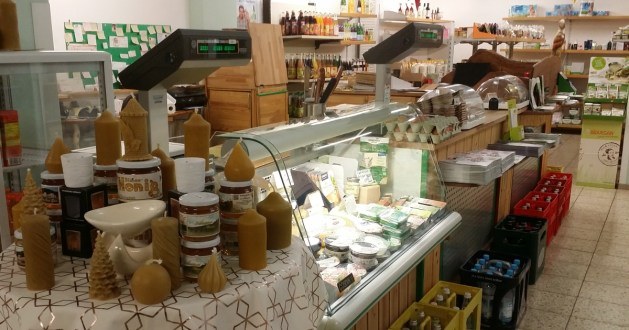 Käse- und Feinkosttheke mit Glasvitrine, Eiern, Honig und Bienenwachskerzen im Vordergrund