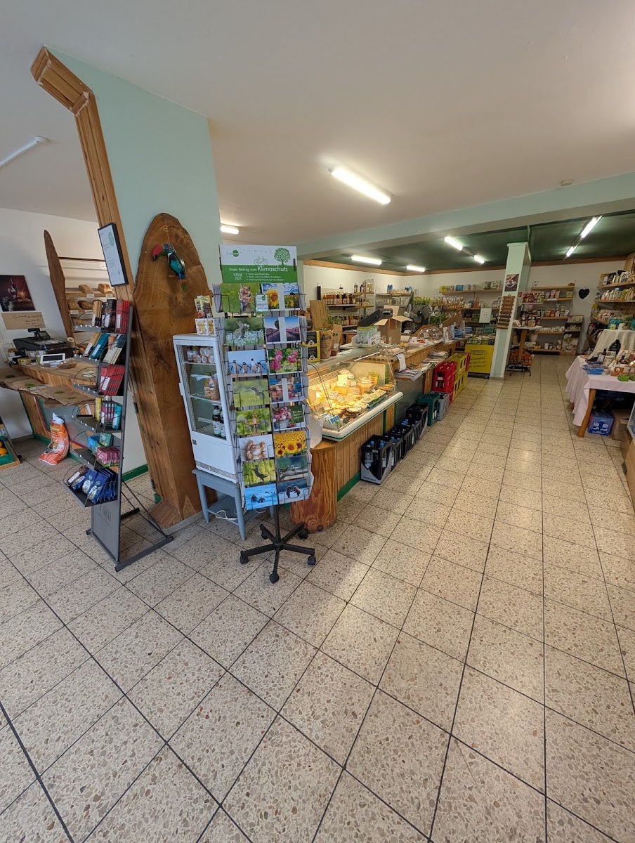 Weiter Blick durch den Grünschnabel Naturkostladen: Brotregal, Zeitschriftenständer, Kühlschrank und Verkaufstheke
