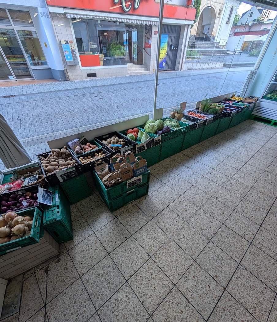 Gemüse- und Obstkisten am Schaufenster mit Kartoffeln, Zwiebeln, Kohl und Karotten, eine Kiste mit Bioland-Aufdruck